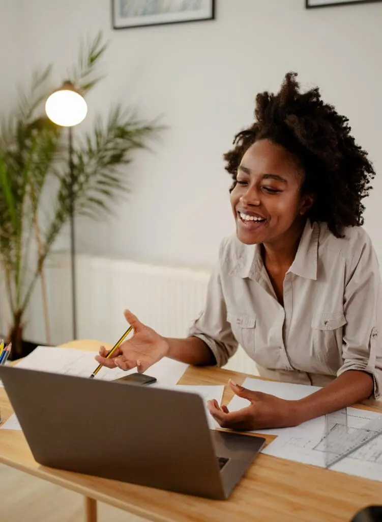 Image of happy black woman, smiling while speaking or chatting o business woman using a laptop in home office