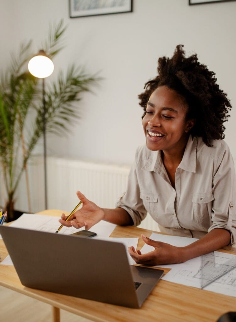 Image of happy black woman, smiling while speaking or chatting o business woman using a laptop in home office